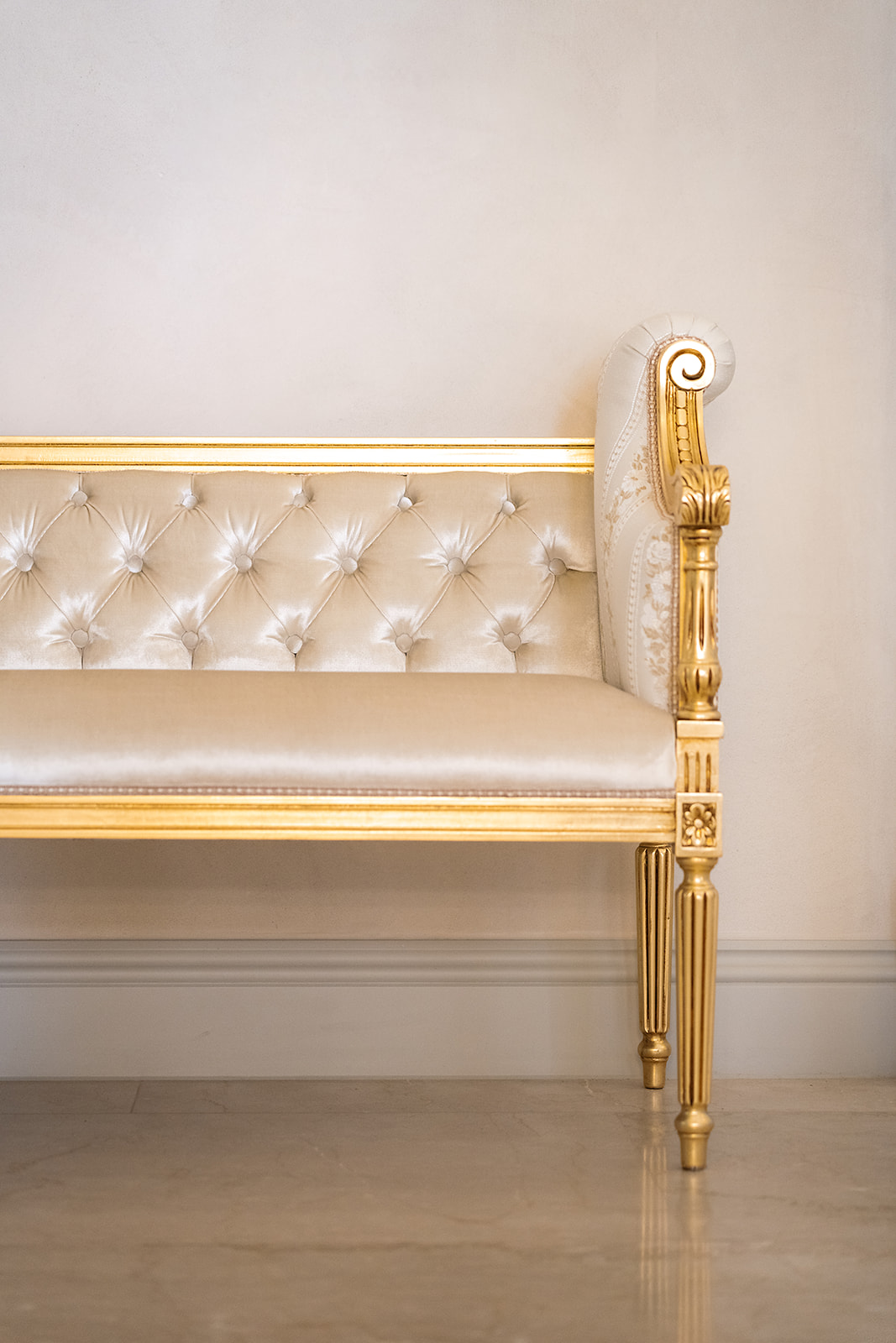 Giltwood tufted settee against a chalk wall