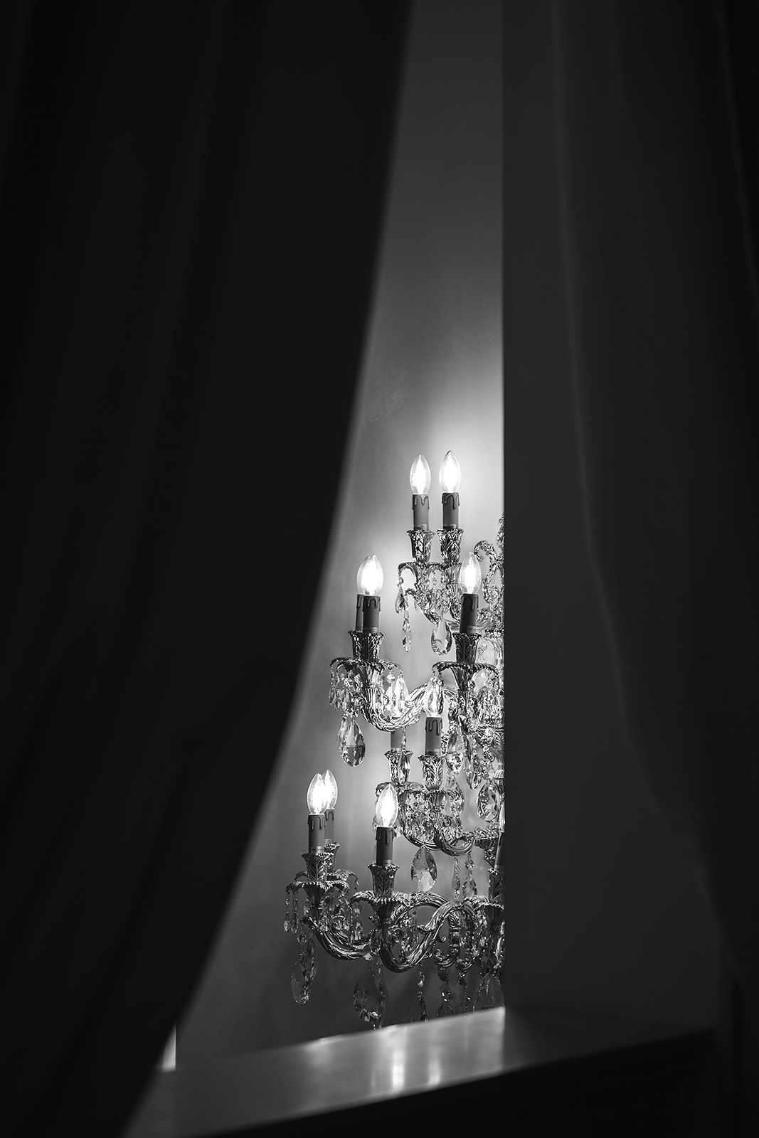 Crystal wall sconce glimpsed between drawn curtains